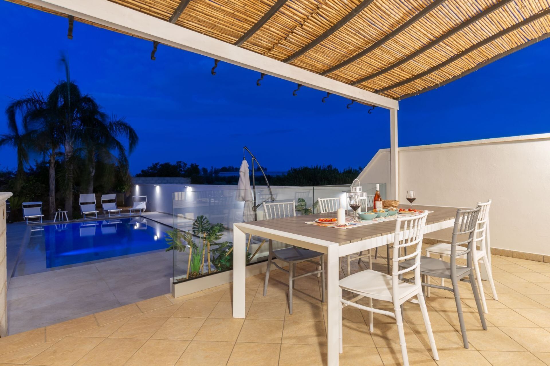 An outdoor dining area with a pool and lounge chairs.