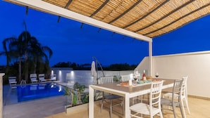 An outdoor dining area with a pool and lounge chairs.