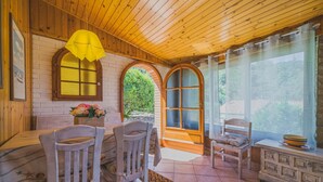 A wooden interior with a dining area, a window with a view of greenery, and a bench. - UN GIARDINO SU PARETI (Capoliveri)