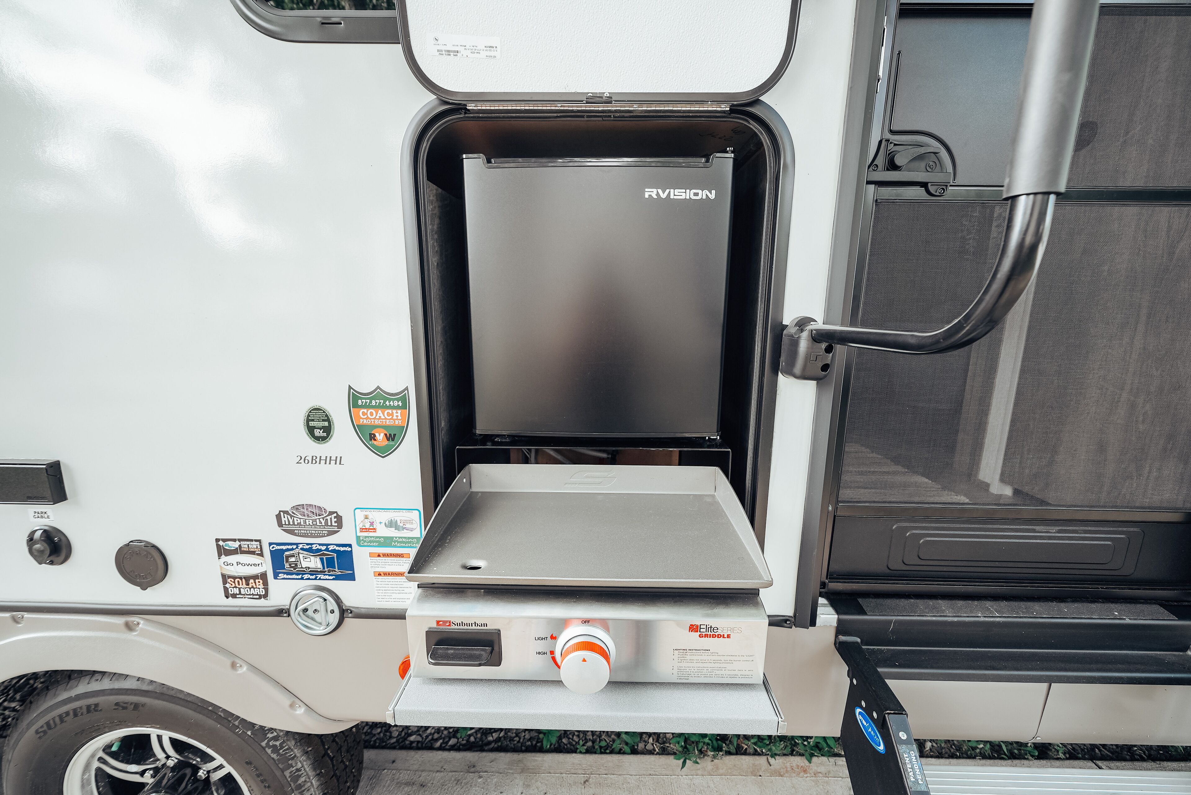 A compact RV with a sliding door, a solar panel, and a compact kitchenette.