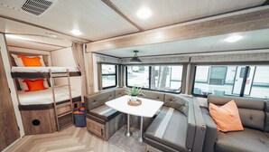 Een gezellig interieur met een stapelbed, een zithoek met een tafel, en grote ramen met uitzicht.