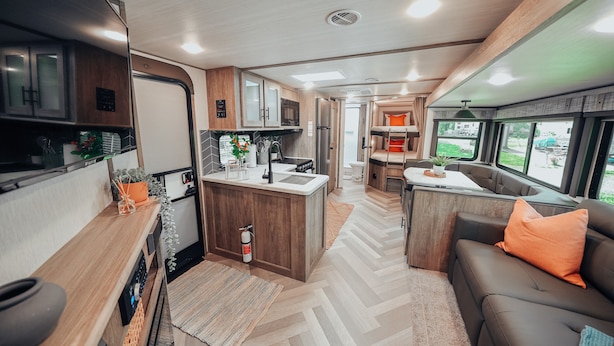 Een compact camperinterieur met een kitchenette, een eethoek en een zithoek met uitzicht.