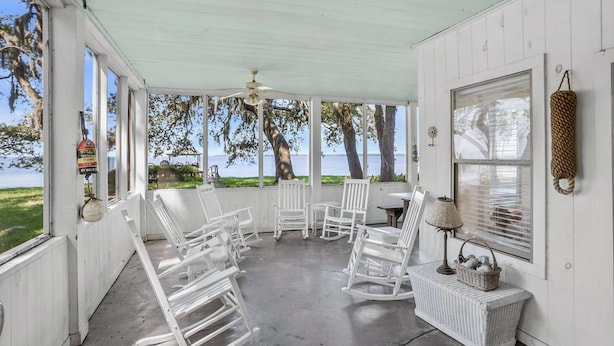 A covered porch with white rocking chairs, a table, and a basket. - Family Paradise on Lands End - Private Dock (Saint Helena Island)