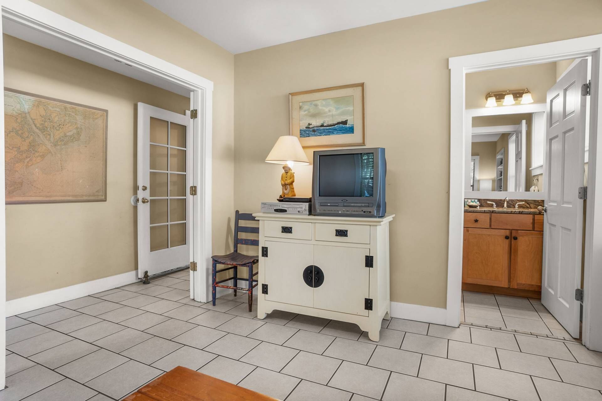A hallway with a vintage television set on a cabinet, a lamp, and a framed picture on the wall.
