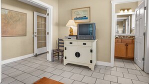 A hallway with a vintage television set on a cabinet, a lamp, and a framed picture on the wall. - Family Paradise on Lands End - Private Dock (Saint Helena Island)