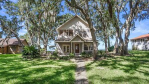 A two-story house with a porch, surrounded by trees and a pathway leading to the entrance. - Family Paradise on Lands End - Private Dock (Saint Helena Island)