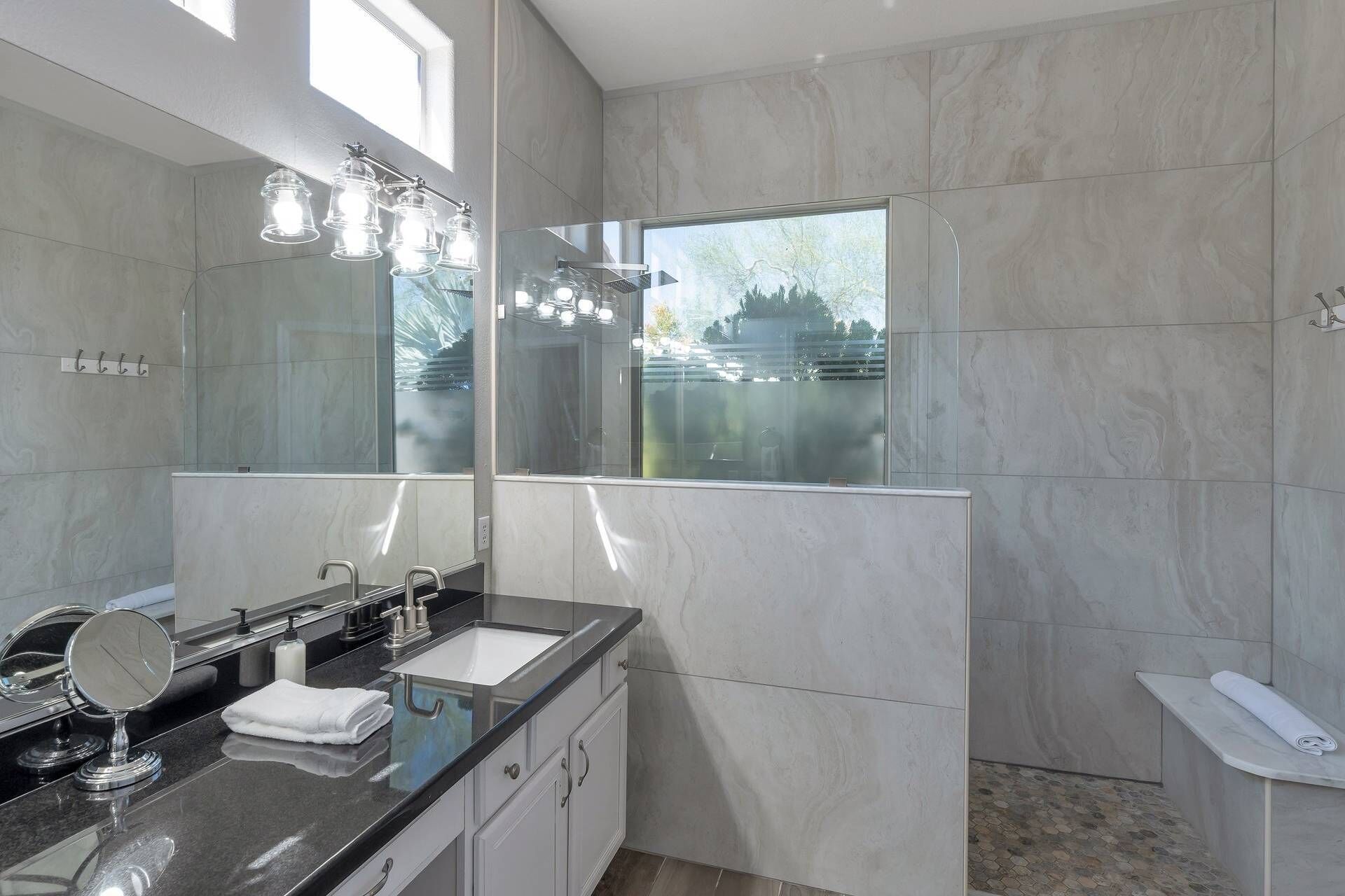 A modern bathroom with a large mirror, a sink with a vanity, and a shower area.
