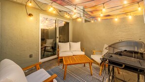 Eine Außenpatio mit Grill, Sitzgruppe und Lichterkette.