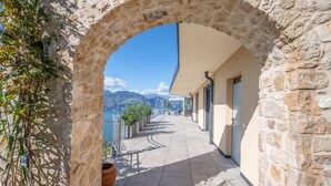 Ein Steingewölbe führt zu einem Balkon mit Blick auf Berge und ein Gewässer.