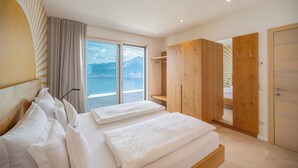 Ein modernes Hotelzimmer mit einem großen Bett, einem Holzschrank und einem Balkon mit Blick auf die Berge.