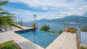 Ein Schwimmbad mit freiem Blick auf einen See und Berge im Hintergrund.