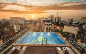 A rooftop pool with a cityscape view at sunset.