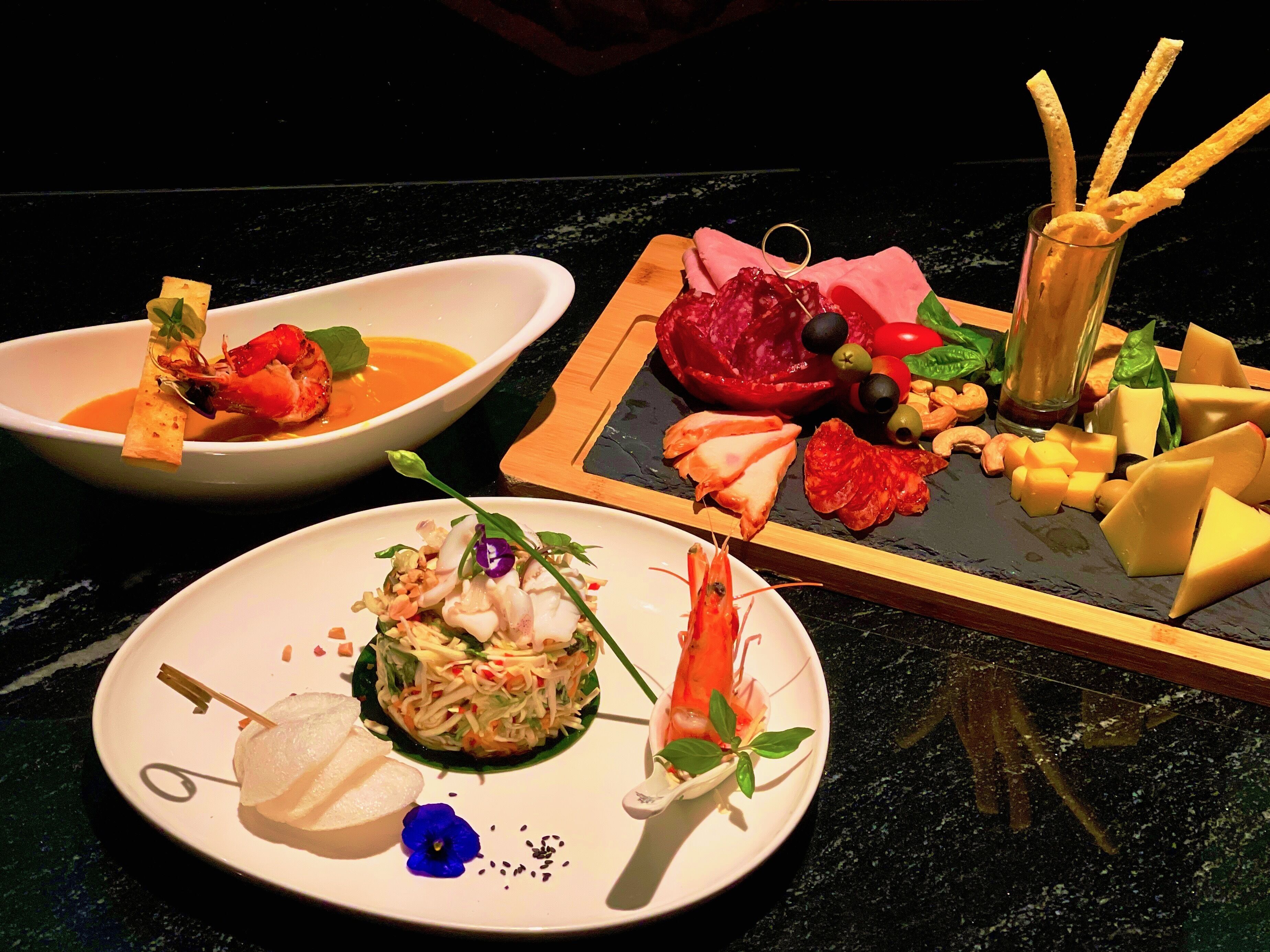 A variety of dishes on a table, including seafood, cheese, and vegetables.
