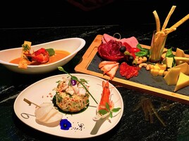 A variety of dishes on a table, including seafood, cheese, and vegetables.