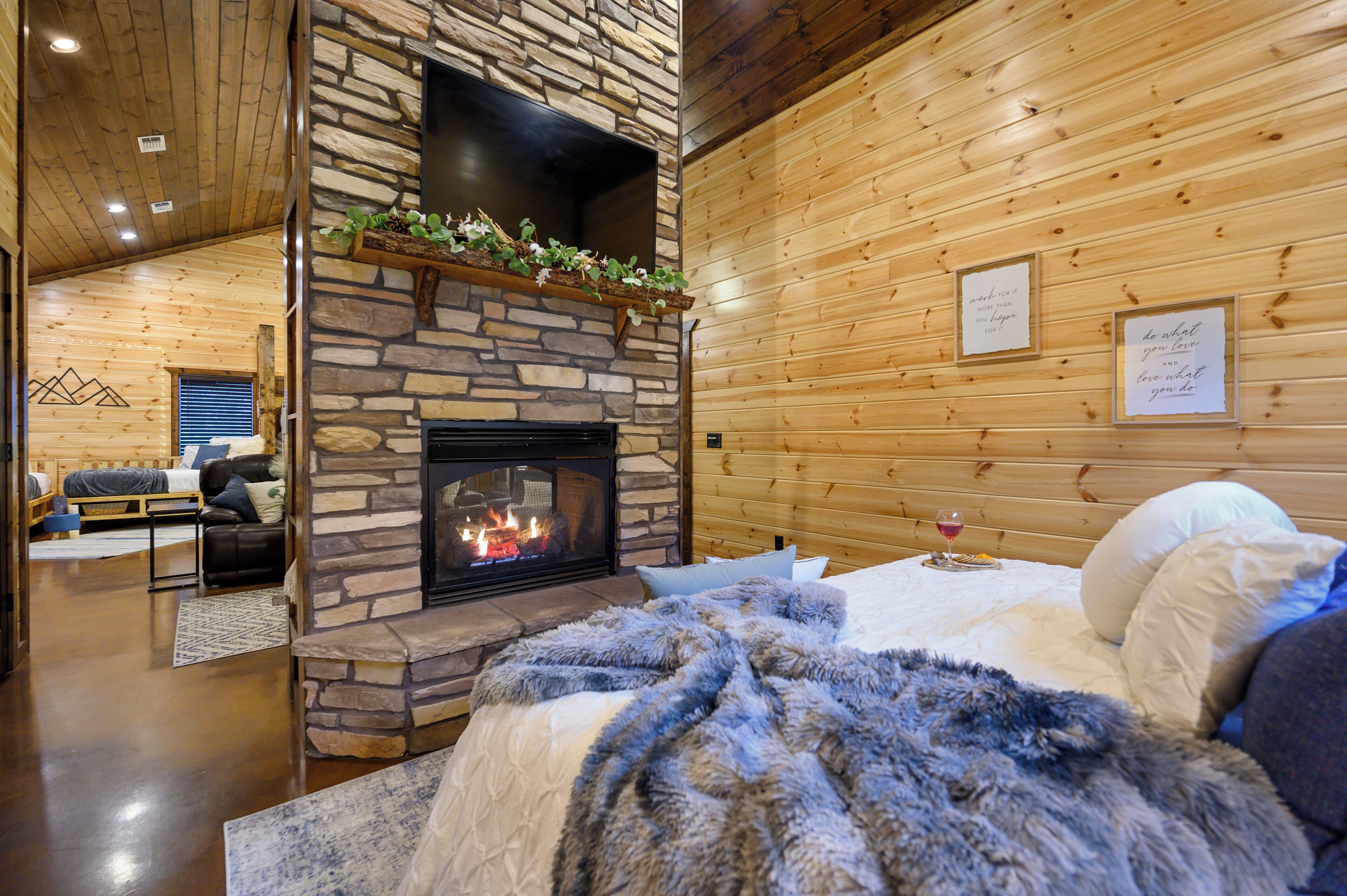 A cozy log cabin interior with a stone fireplace, wooden walls, and a comfortable seating area.
