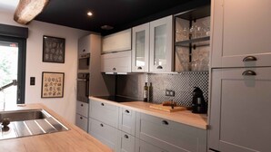 Une cuisine moderne avec des meubles gris, un plan de travail en bois et des appareils électroménagers en acier inoxydable.