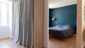 Une chambre à coucher avec un lit, un plancher en bois, des rideaux gris et un mur bleu.