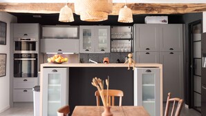 Une cuisine moderne avec des meubles de couleur grise, un îlot central et une table à manger en bois.