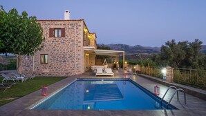 Un bâtiment en pierre doté d’une piscine, d’un espace extérieur aménagé et offrant une vue sur les montagnes.
