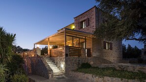 Un bâtiment en pierre doté d’un espace extérieur couvert et d’un escalier menant à l’entrée.