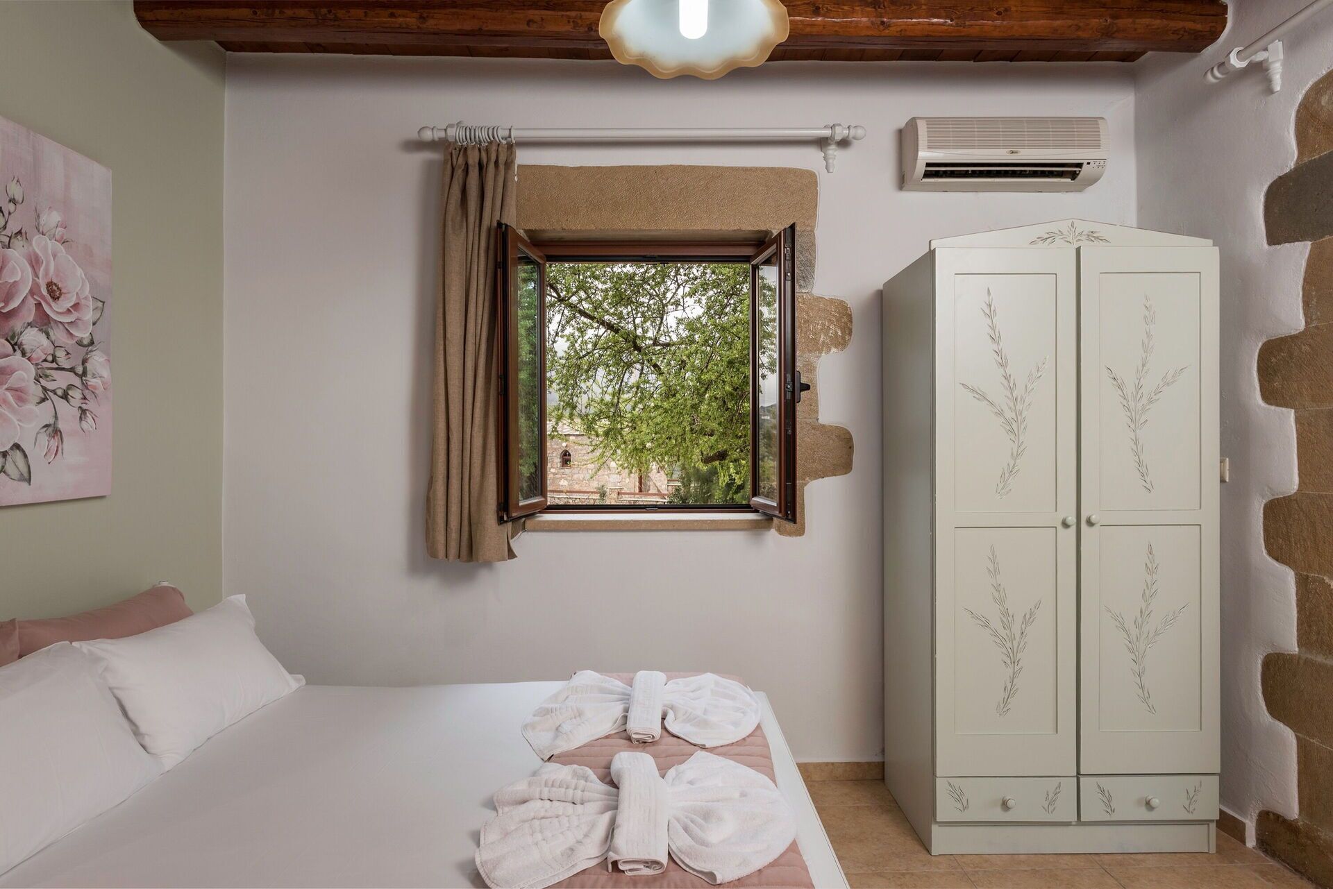 Une chambre à coucher avec un lit, une fenêtre avec des rideaux, une armoire et un appareil de climatisation.