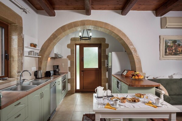 Une cuisine avec une porte en arc de cercle, un coin repas avec une table mise pour le petit-déjeuner et un tableau accroché au mur.