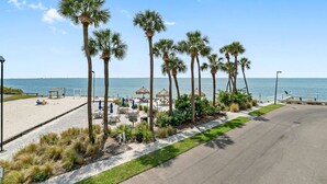 Eine Strandpromenade mit Palmen, Liegestühlen und Sonnenschirmen.