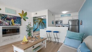 Eine moderne Küche mit Kühlschrank, Mikrowelle und Barhocker.