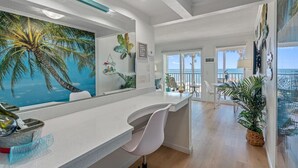 Eine moderne Küche mit einer großen Kochinsel, Meerblick und einem tropischen Wandbild.