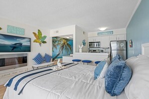 A bedroom with a bed, a TV, a painting, and a kitchen area with a refrigerator. - Fun-N-Sun with Spectacular Ocean Views (Tampa)