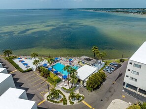 An aerial view of a hotel with a swimming pool, parking area, and a view of the ocean. - Fun-N-Sun with Spectacular Ocean Views (Tampa)
