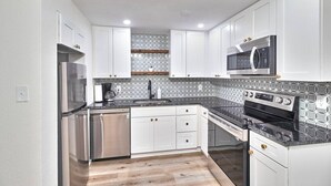 Una cocina moderna con armarios blancos, electrodomésticos de acero inoxidable y un salpicadero con diseño.