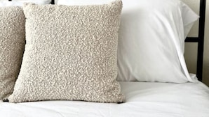 Una cama con cabecera de metal negro, dos almohadas y ropa de cama blanca.