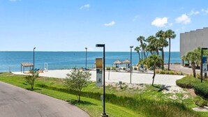 A beachside hotel with a view of the ocean, outdoor seating, and palm trees.