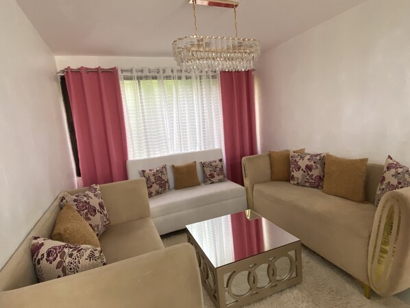 A living room with a sofa, armchairs, a coffee table, and a chandelier.
