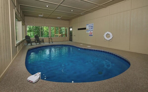 An indoor swimming pool with a lifebuoy, a chair, and a pool ladder. - Swim Year-Round, Sip Fireside, Host Movie Nights, Play Pool & Soak in the Hot Tub - Mystic Timber (Sevierville)