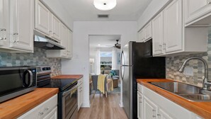 A modern kitchen with white cabinets, a black refrigerator, and a microwave. - PCB Modern Beach Casita, Fully Fenced Yard (Panama City Beach)