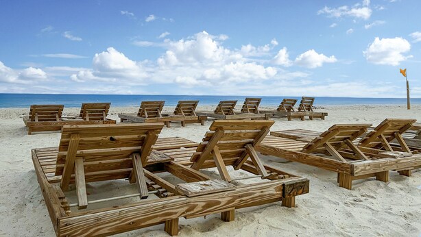 A beach with wooden lounge chairs arranged in rows. - PCB Modern Beach Casita, Fully Fenced Yard (Panama City Beach)