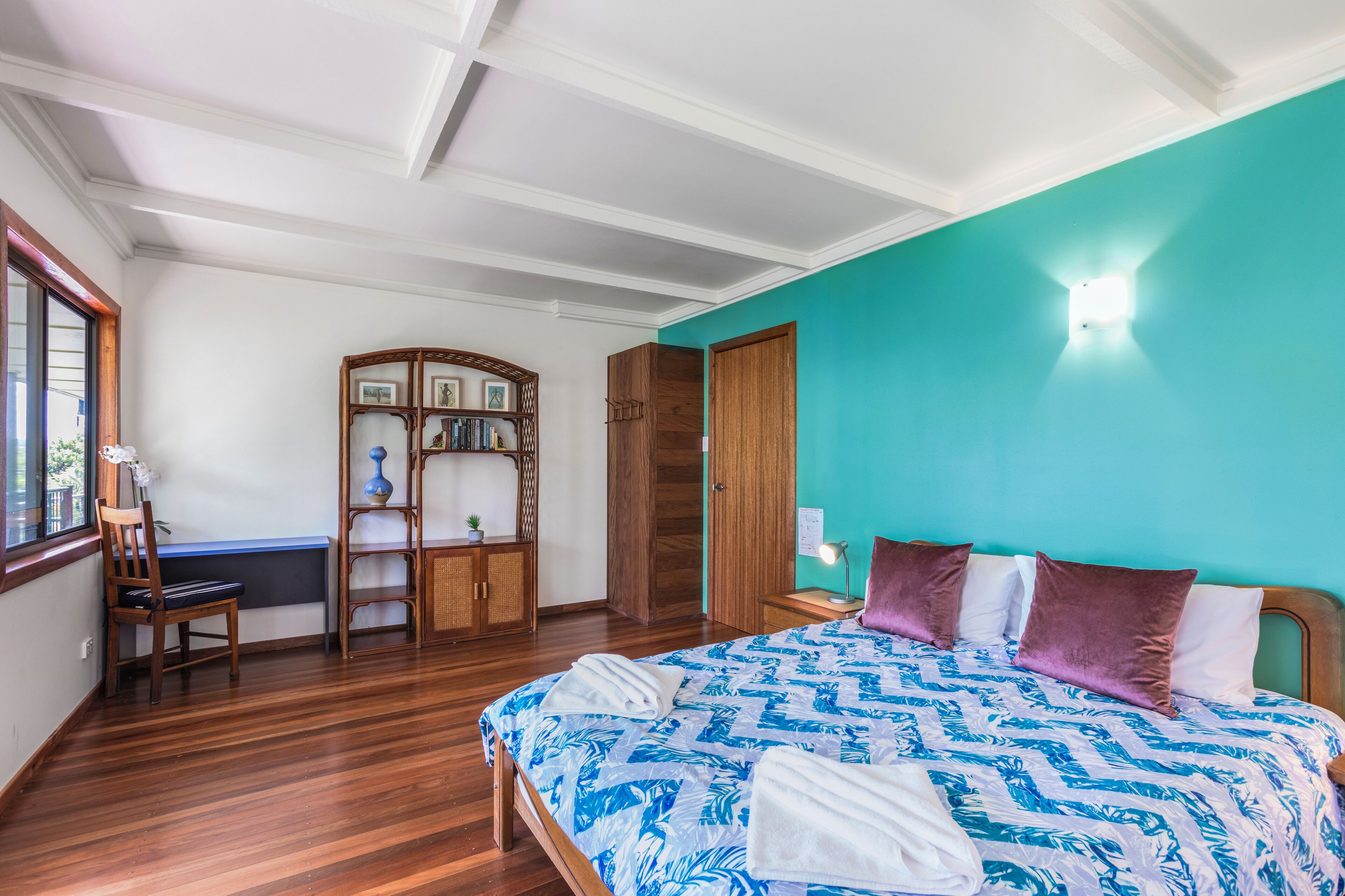Una camera da letto con un letto, un'armadio in legno e una scrivania con una sedia.