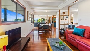 A spacious living room with a large flat-screen TV, a red leather sofa, and a dining area with wooden furniture. - Farrants Hill (Farrants Hill)