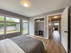 Un dormitorio con una cama grande, un vestidor y vistas al jardín trasero.