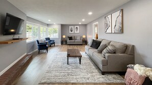 A spacious living room with a large TV, comfortable seating, and artwork on the walls. - Excellent location, close to Olympic National Park, restaurants & grocery stores (Port Angeles)