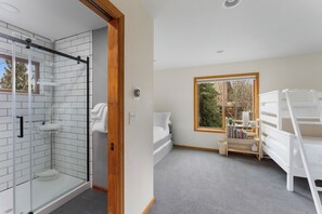 Ein modernes Badezimmer mit einer Duschkabine aus Glas, einer weißen Badewanne und einer Holztür.