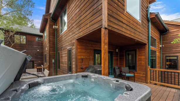 A wooden cabin with a hot tub and outdoor seating area.