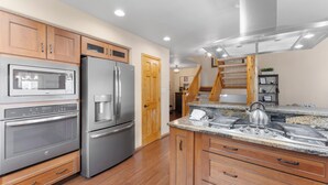 A modern kitchen with stainless steel appliances, wooden cabinets, and a granite countertop.
