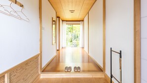A hallway with wooden flooring, a wooden ceiling, and a view to the outside. There are shoes placed at the end of the hallway. - Resort stay Bowen (Ito)