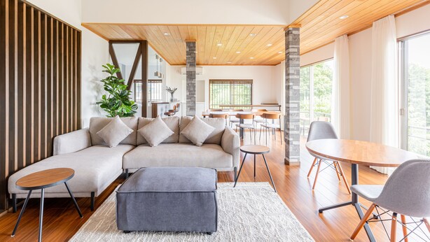 A modern living room with a sectional sofa, a round coffee table, and a dining area with a wooden table and chairs. - Resort stay Bowen (Ito)
