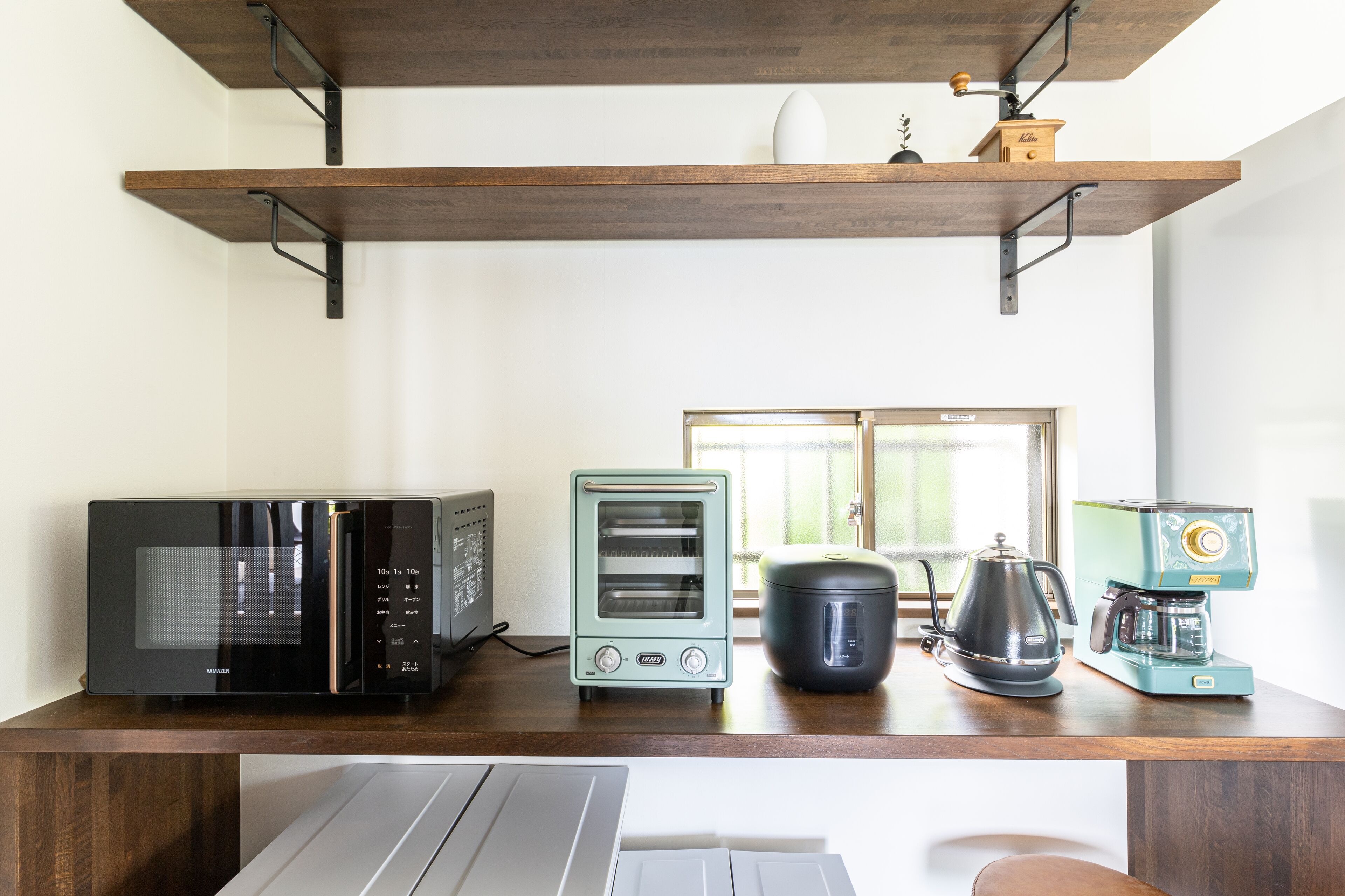 A kitchen with a microwave, toaster, kettle, and coffee maker on a wooden countertop.