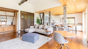 A modern living room with a sofa, ottoman, and dining area with chairs and a table. - Resort stay Bowen (Ito)