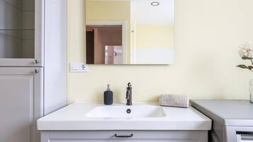 Een badkamer met een wit wastafel, een spiegel, een handdoek en een zeepdispenser.